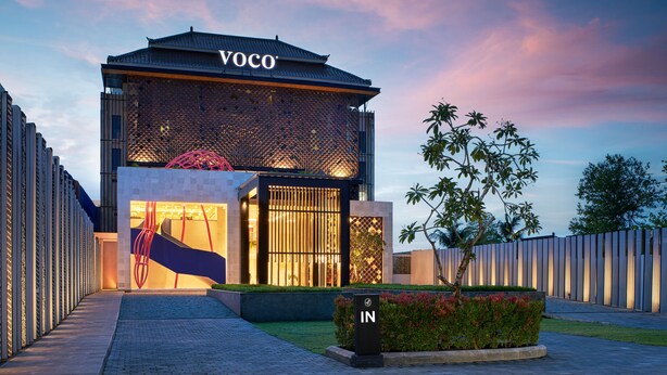A modern building with a prominent "VOCO" sign, a well-lit entrance, and a landscaped garden area. - voco Bali Seminyak by IHG (Keroboken Kelod)