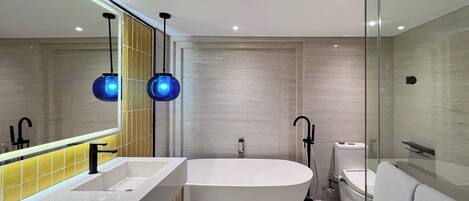 A modern bathroom with a freestanding bathtub, a large mirror, and two pendant lights.