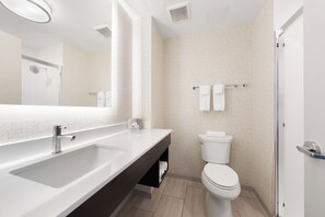 Un baño moderno con un espejo grande, un lavabo, un inodoro y una ducha.
