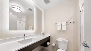 A modern bathroom with a large mirror, a sink, a toilet, and a shower area.