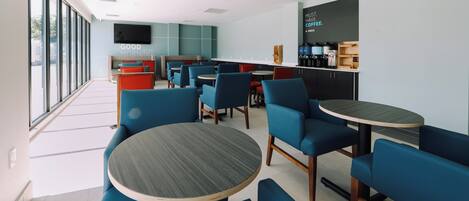 A modern cafe with blue seating, a coffee bar, and a large window.
