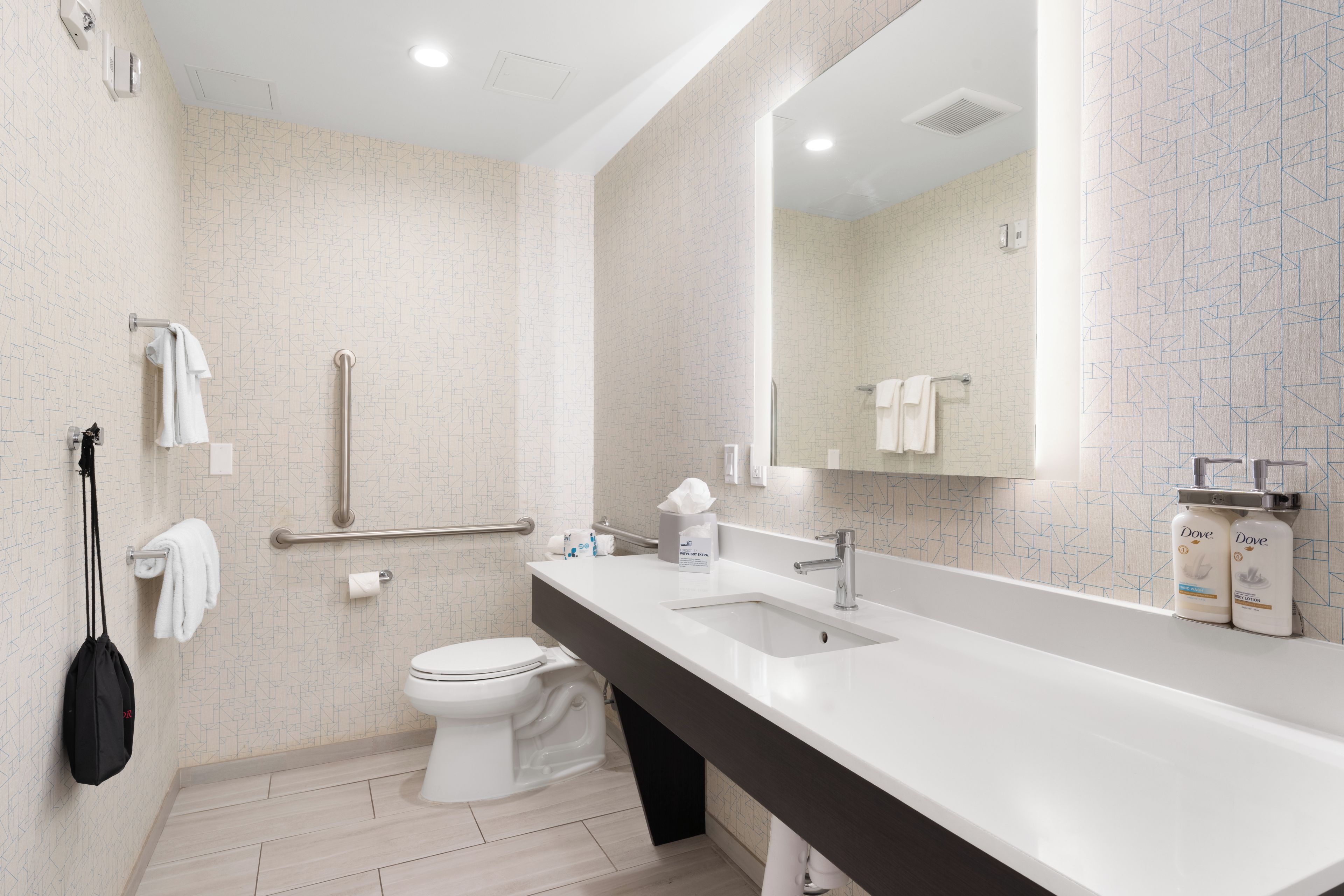 A modern bathroom with a white sink, a toilet, and a large mirror.