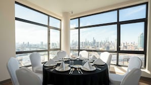 Comedor con una mesa redonda dispuesta para seis personas, amplias ventanas con vistas al horizonte de la ciudad.