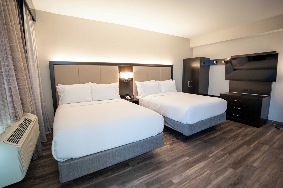 Una habitación de hotel con dos camas, televisión, calefacción y armario.