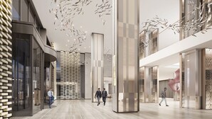 A spacious, modern interior with a high ceiling, a central column, and a patterned wall.