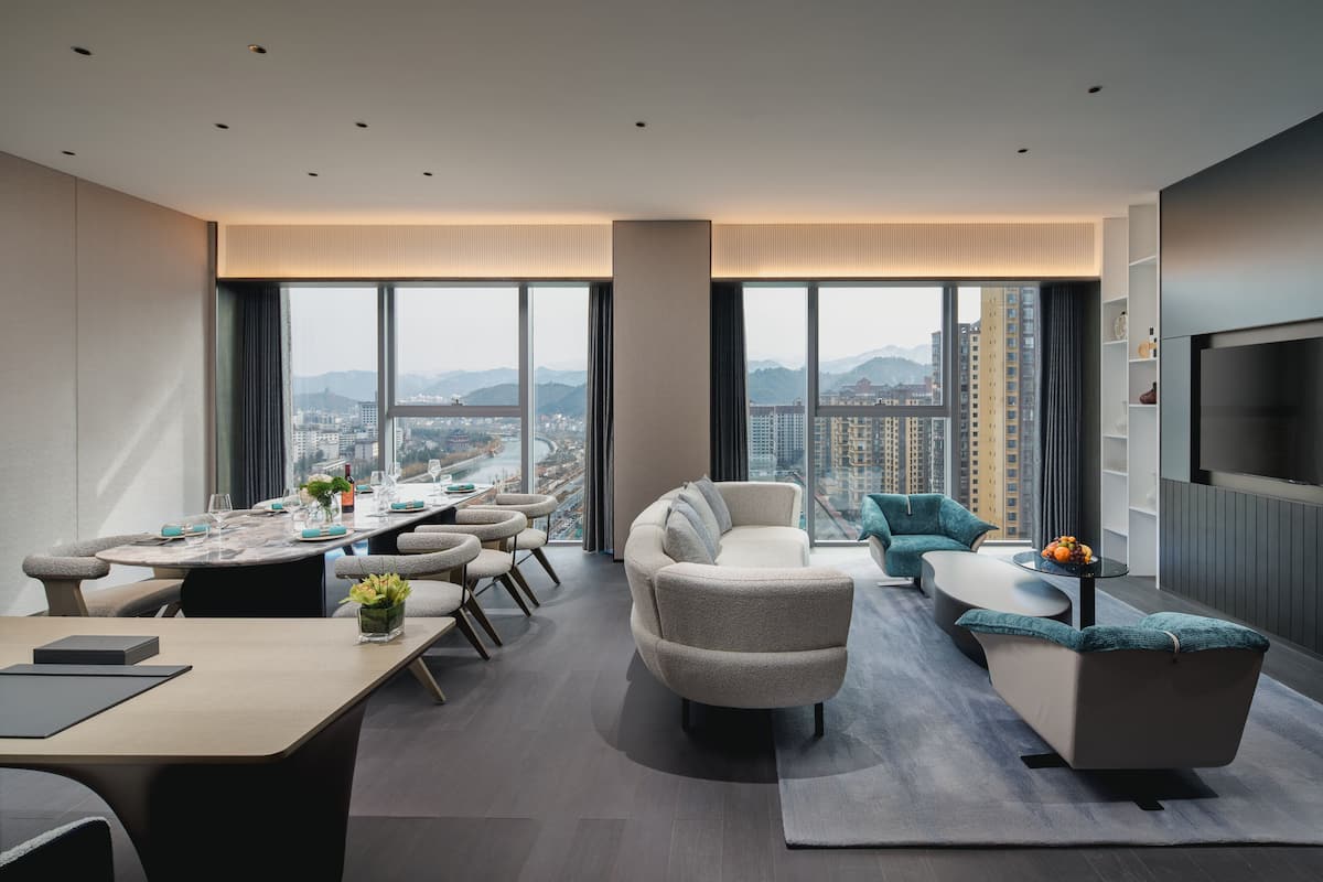 Una sala de estar moderna con comedor, ventanas amplias y vista a la ciudad.
