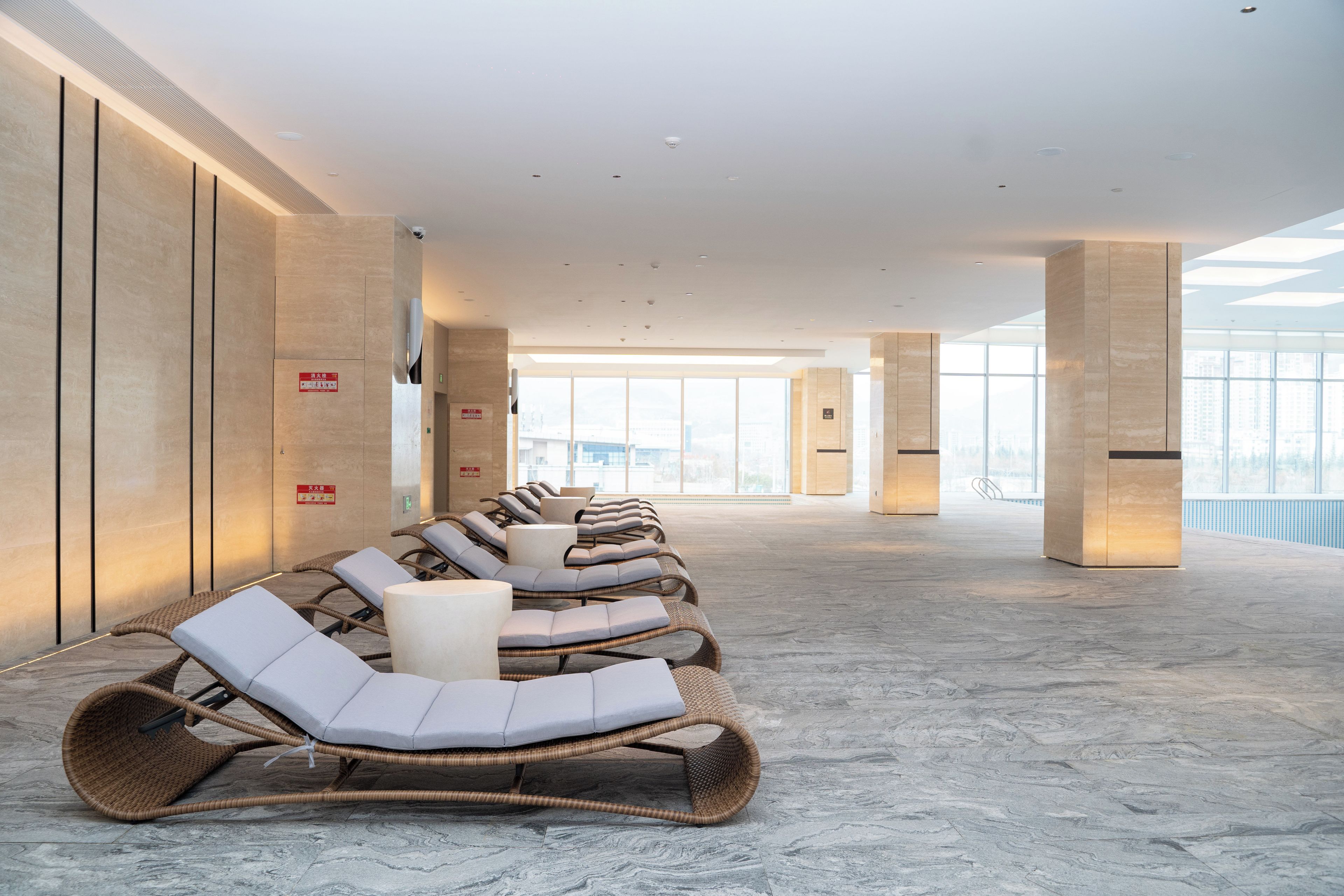 A modern indoor relaxation area with wicker lounge chairs and a marble floor.