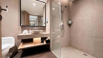 Un baño moderno con cabina de ducha de vidrio, un espejo grande y un mueble de tocador de madera con lavamanos.