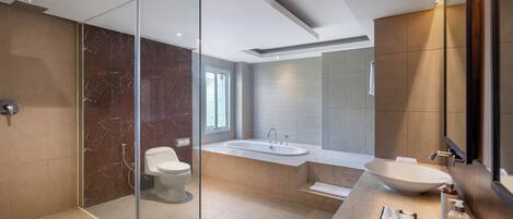 A modern bathroom with a glass shower enclosure, a freestanding bathtub, a large sink, and a vanity with toiletries.