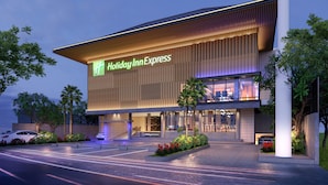 A Holiday Inn Express hotel with a modern design, featuring a prominent entrance, landscaped gardens, and a parking area.