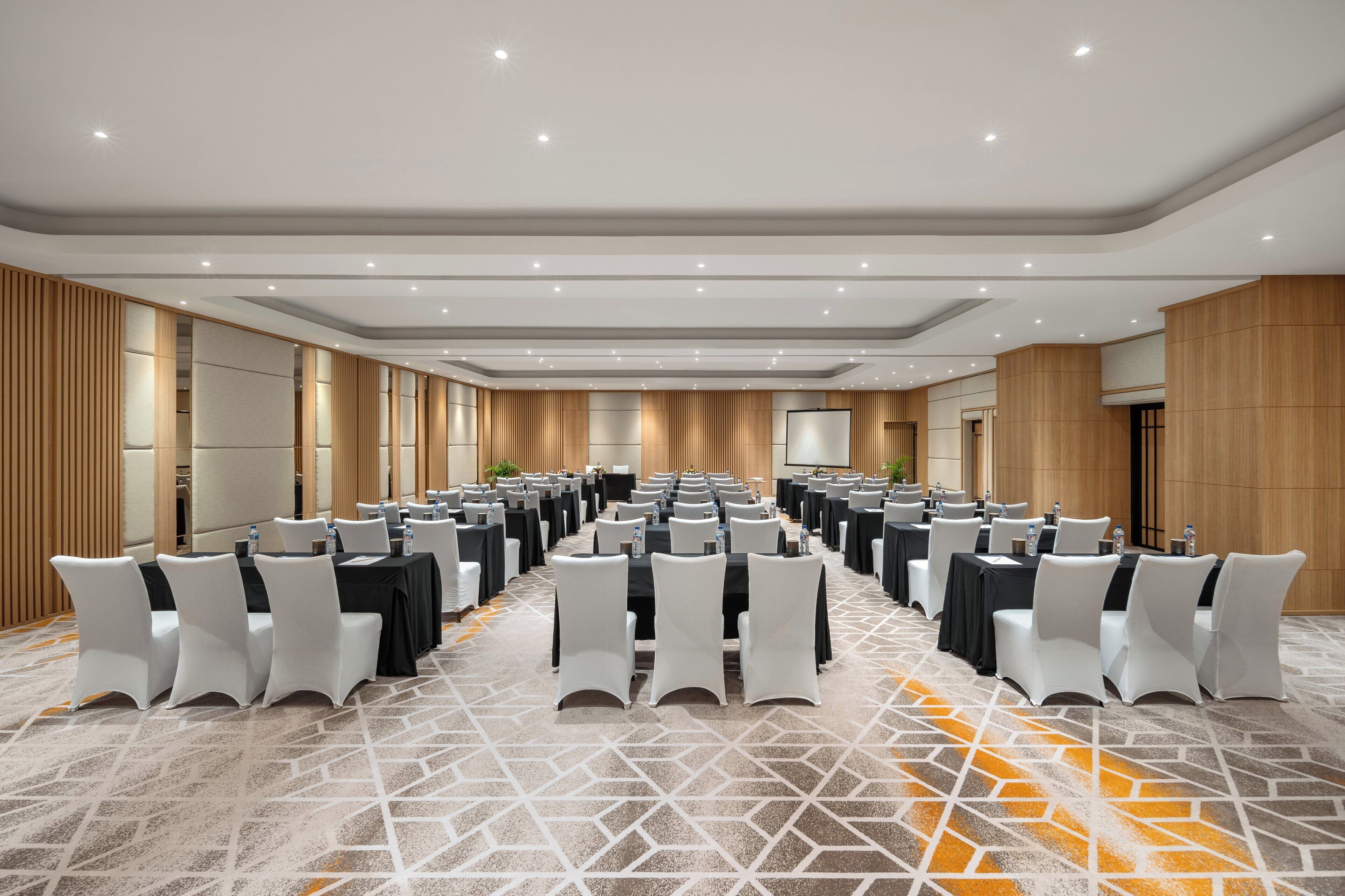 A conference room with rows of tables and chairs, equipped with water bottles and nameplates.