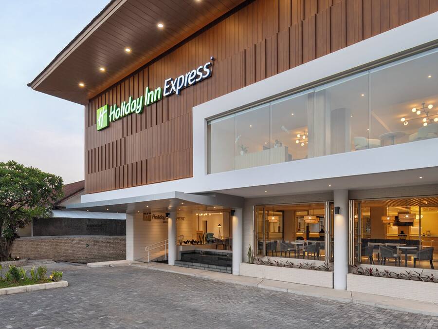 A Holiday Inn Express building with a modern design, featuring a prominent sign, large windows, and a spacious entrance area.