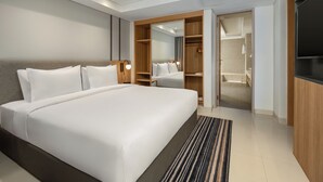 A modern hotel room with a large bed, a walk-in closet, and a TV.