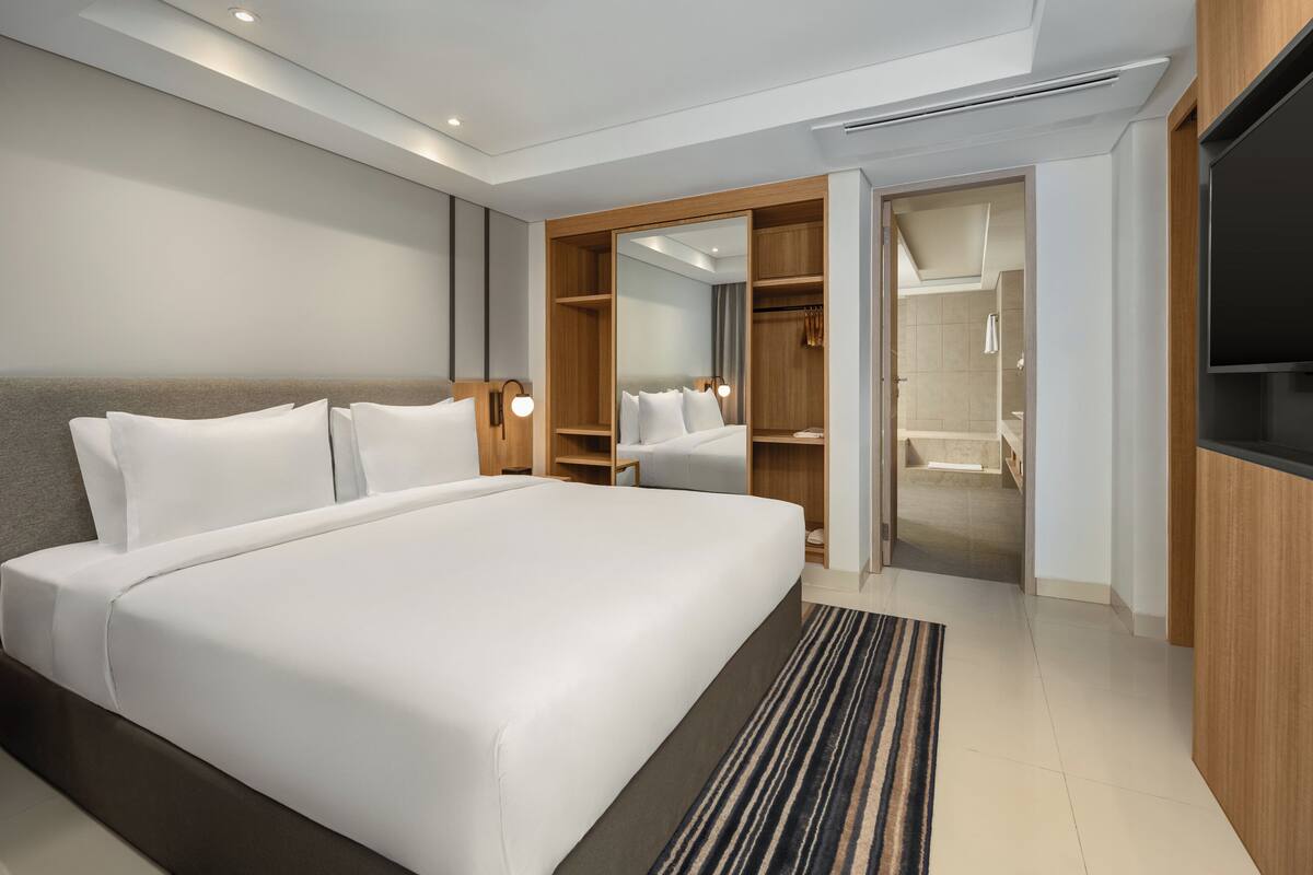 Une chambre d’hôtel moderne dotée d’un grand lit, d  ’un dressing et d’une télévision.