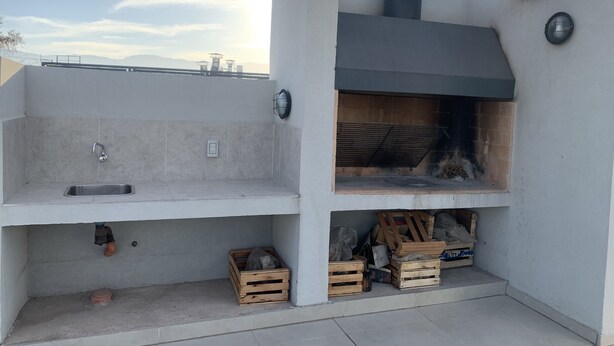 A modern outdoor kitchen with a built-in grill, a sink, and storage space.