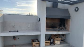 Una cocina exterior moderna con una parrilla empotrada, un lavamanos y espacio de almacenamiento.