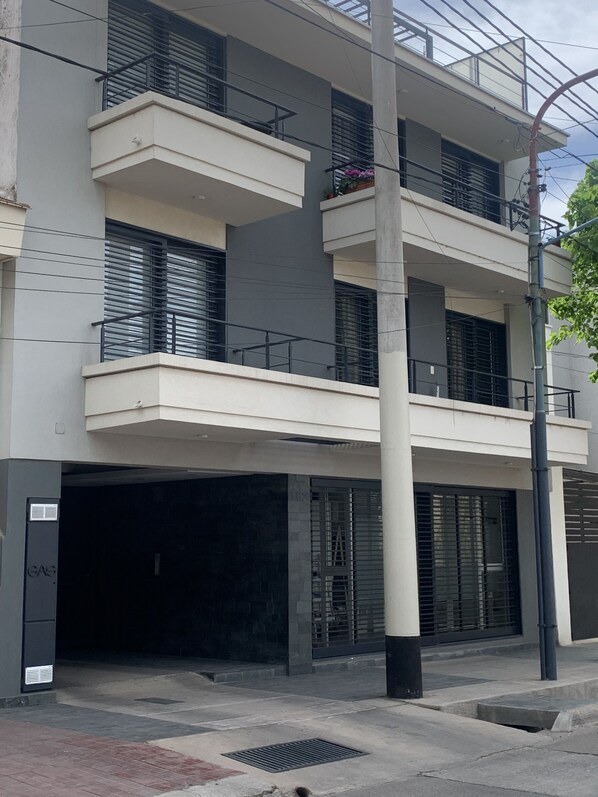 Un edificio de varios pisos con balcones, entrada de garaje y un poste de electricidad.