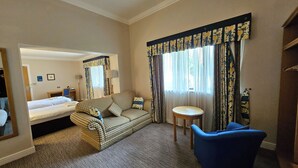 Une chambre d’hôtel avec un lit, un canapé, une chaise, une petite table et un miroir.