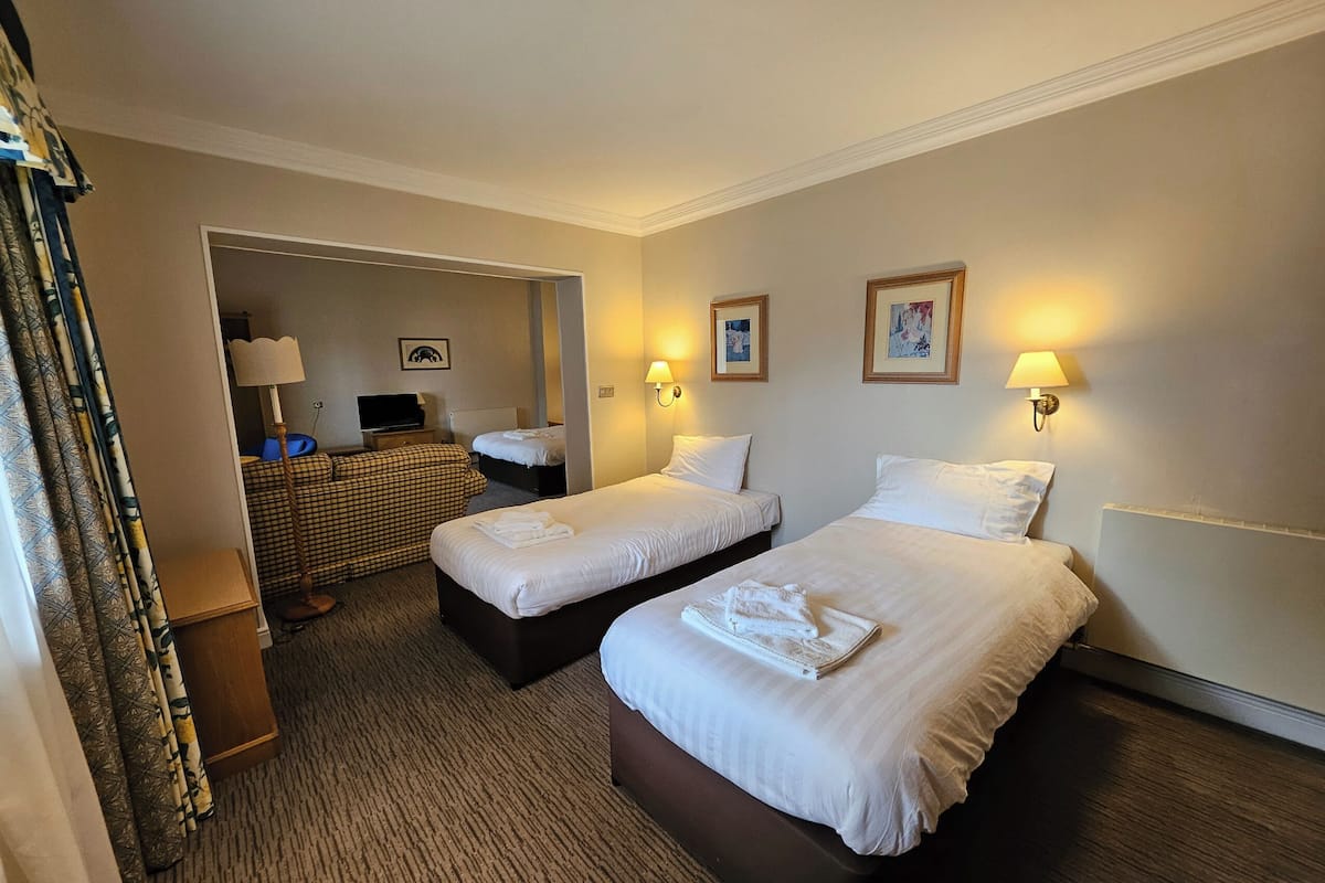 Une chambre d’hôtel avec deux lits, un canapé, une télévision et une lampe.