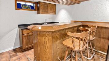 A kitchen with wooden cabinets, a bar area with stools, and a sign above the window reading "Season's Greetings".