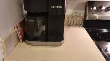 Una cafetera Keurig sobre una encimera de cocina, con un armario encima.