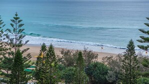 Una playa con olas, una bandera y árboles.