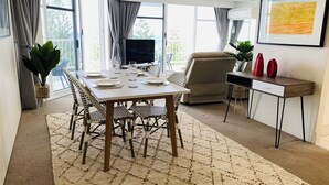 Un comedor con una mesa preparada para cuatro personas, un televisor y un escritorio con ordenador.
