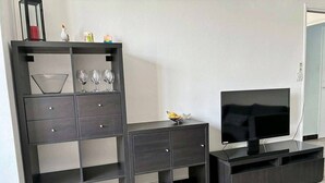 A modern living room with a TV, dark wooden furniture, and a patterned rug.