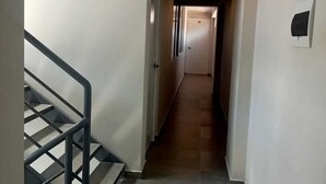 A narrow hallway with a staircase on the left and a door at the end. - MMARROS INN PERU (Cusco)