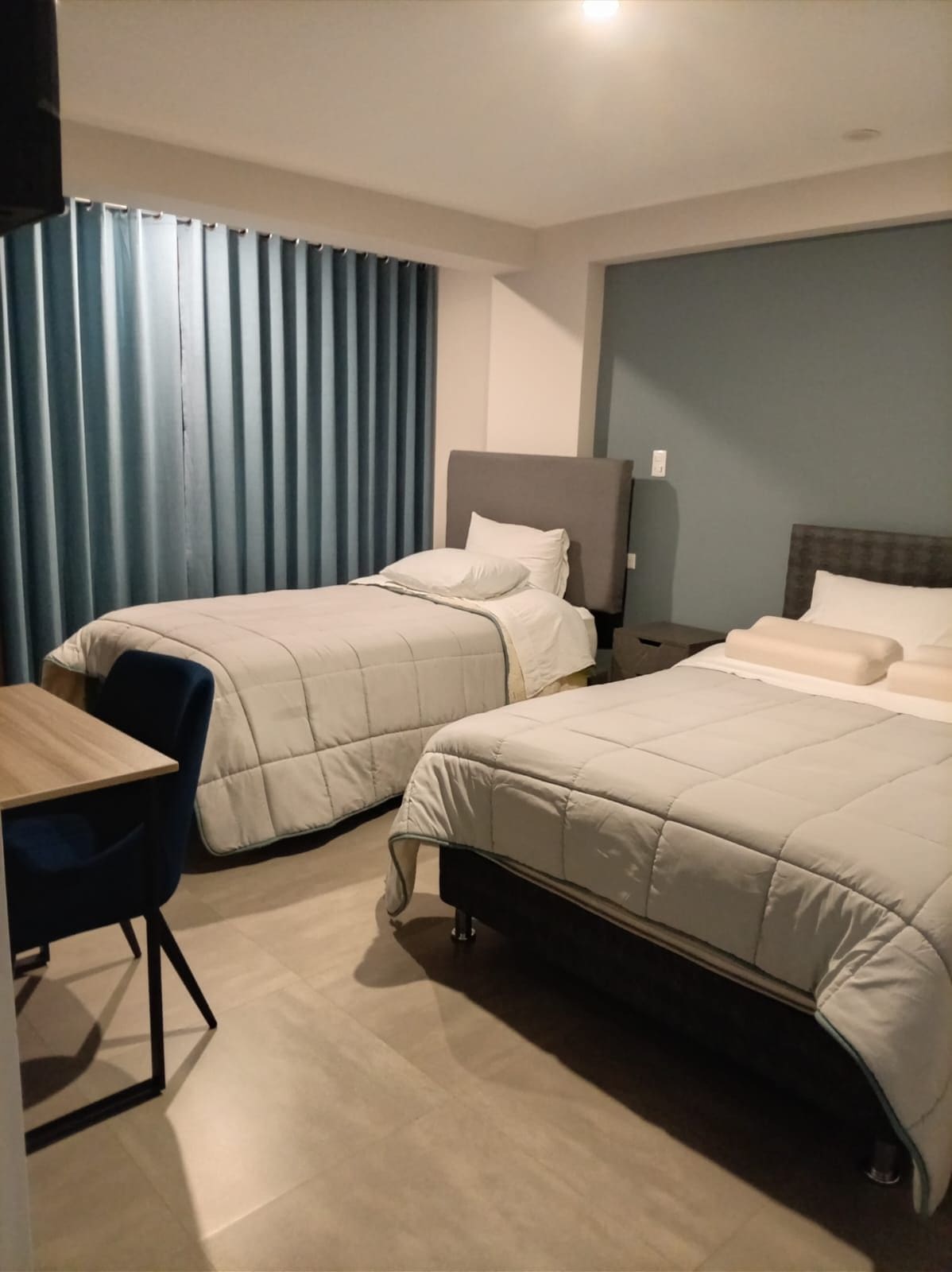 Habitación de hotel con dos camas, un escritorio y una silla.