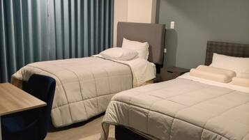 A hotel room with two beds, a desk, and a chair.