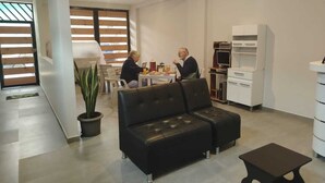 A modern living room with a black leather sofa, a dining table with chairs, and a kitchen area with white cabinets and appliances. - MMARROS INN PERU (Cusco)