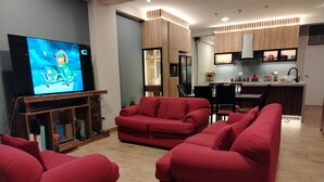 A modern living room with a red sofa set, a flat-screen TV, and a wooden entertainment unit. - MMARROS INN PERU (Cusco)