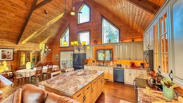 A spacious kitchen with a large island, wooden ceiling beams, and ample natural light from windows.