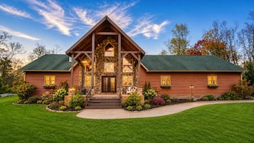 A log cabin with a stone facade, a prominent front porch, and a well-maintained lawn.