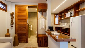 A compact kitchen with wooden cabinetry, a microwave, and a refrigerator. - Villa Nanui Jeri (Jijoca de Jericoacoara)