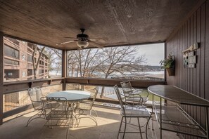A covered outdoor area with a table and chairs, a ceiling fan, and a view of a snowy landscape.