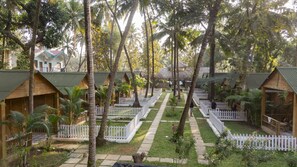 Cabins with peaked roofs are surrounded by a white picket fence and lush vegetation.