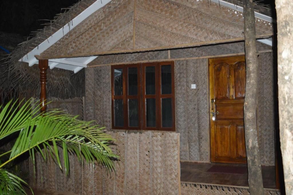 A small, rustic building with a thatched roof, a wooden door, and a window.