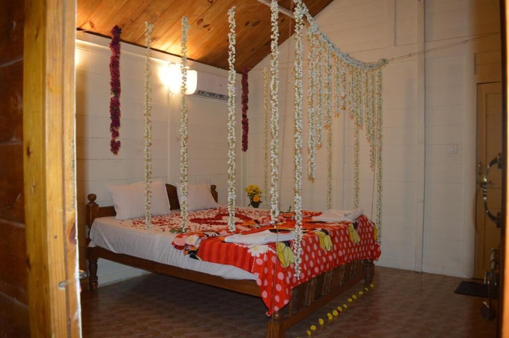 A bedroom with a wooden bed, white walls, and a wooden ceiling.