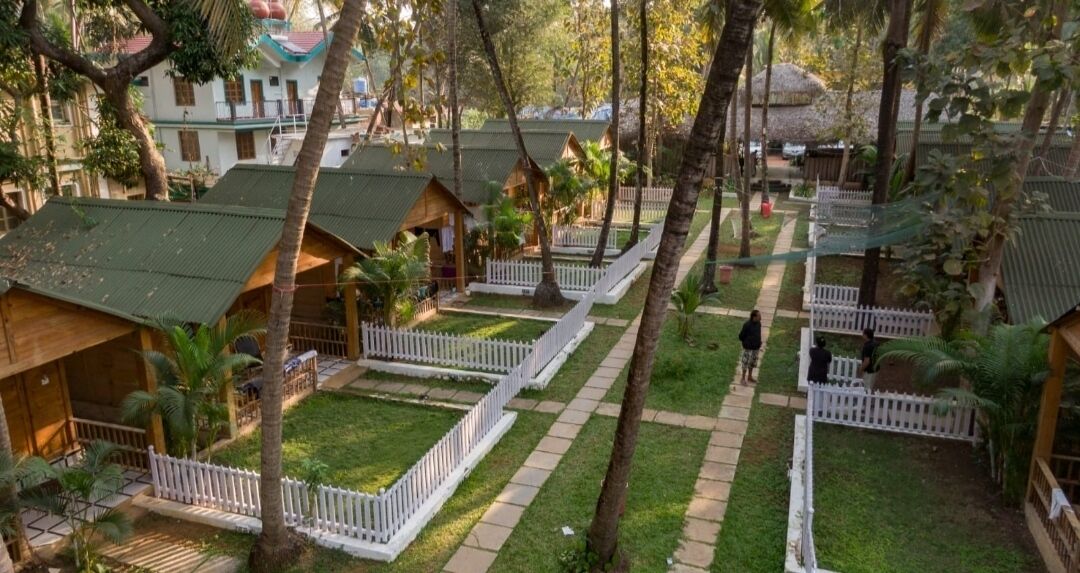 Un resort con cabañas de madera, cercas blancas en estilo americano y un césped bien cuidado.