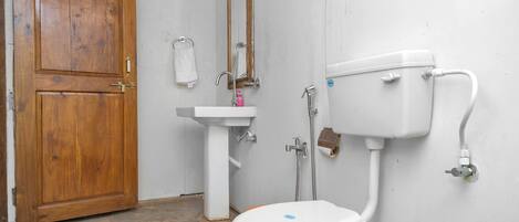 A bathroom with a wooden door, a sink, a mirror, and a toilet.