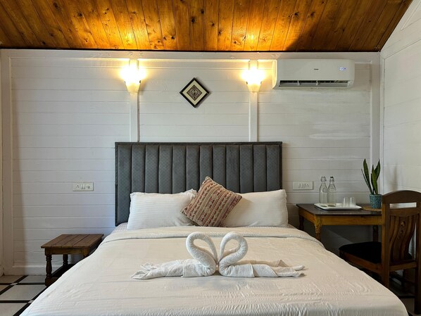 Relax in a serene space with a neatly made bed, decorative towel arrangement, and a small potted plant.