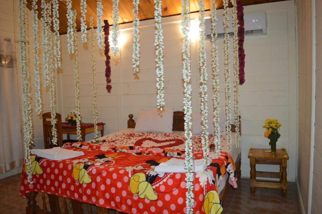 A room with a bed covered in a polka dot blanket, a wooden headboard, and hanging floral decorations.