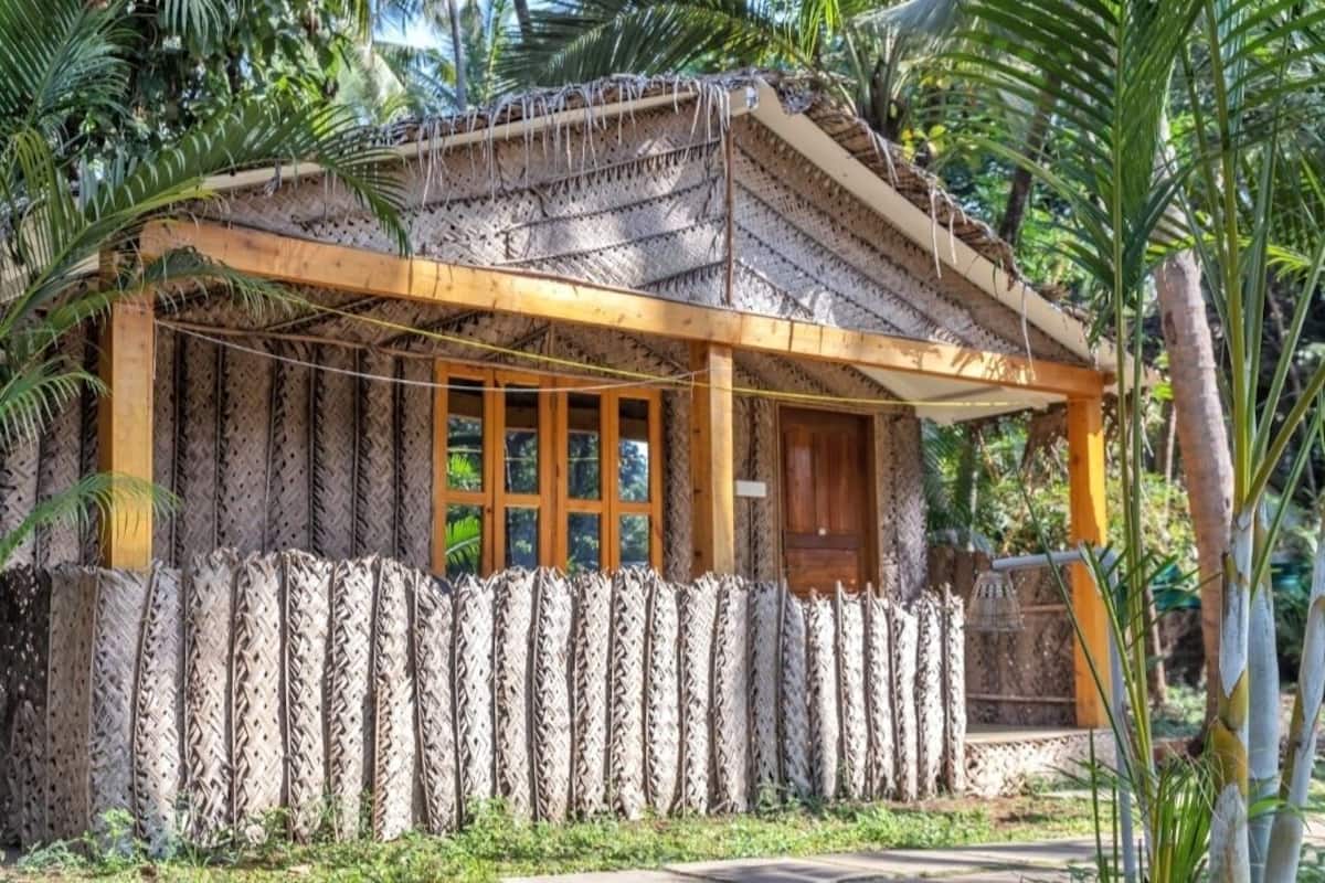 A traditional thatched-roof structure with a wooden porch and a fenced perimeter.