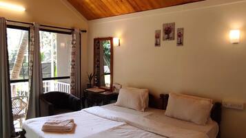 Un dormitorio con techo de madera, una cama grande con ropa blanca, una mesita con espejo y una ventana con cortinas.