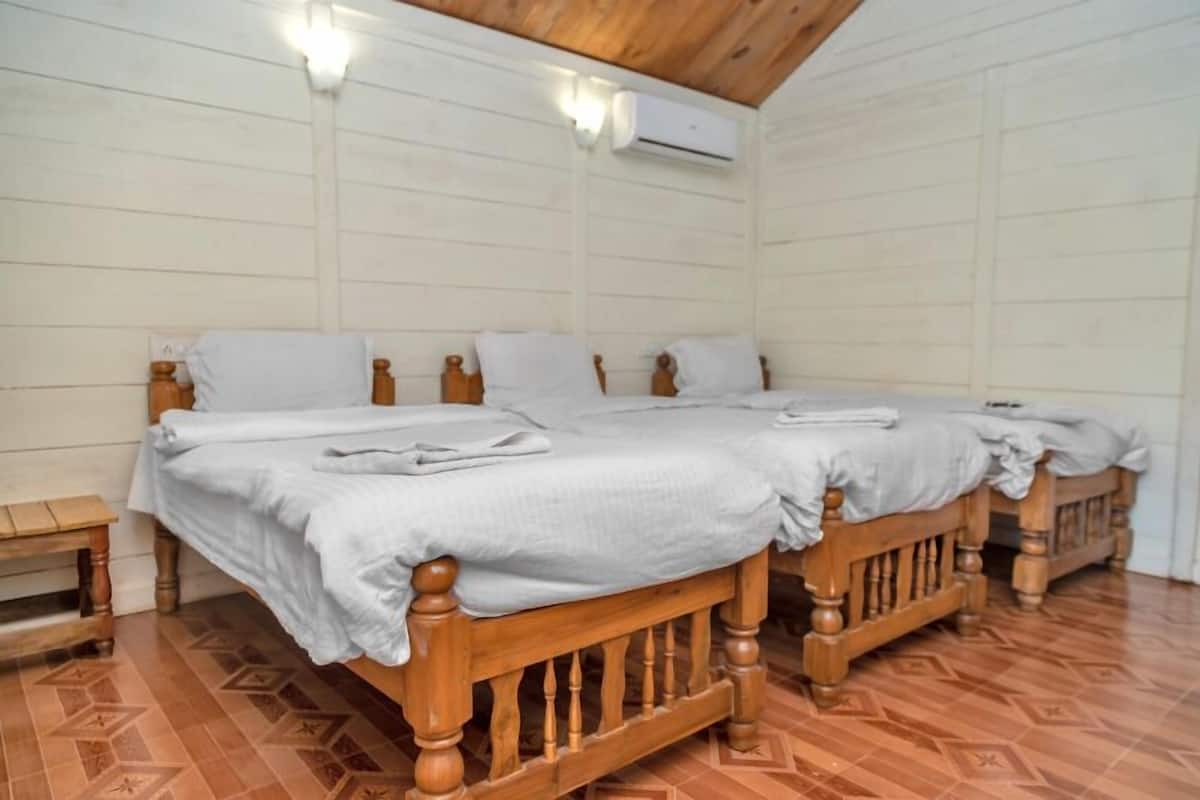 A room with a large bed, two bedside tables, and an air conditioning unit on the wall.