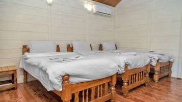 Una habitación con una cama grande, dos mesitas de noche y un equipo de aire acondicionado en la pared.