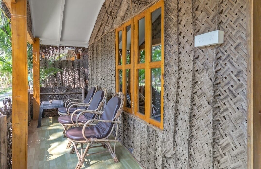 A covered outdoor seating area with wicker chairs and a woven wall.