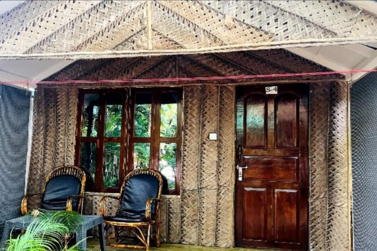 A room with a wooden door, two wicker chairs, and a window.